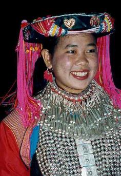 China | Lisu women make their clothing of brightly coloured cloth.   They wear multi coloured tunics with a wide black belt and  pants.    Sleeves shoulders and cuffs are heavily embroidered with narrow bands of blue. red and yellow.  The more affluent wear massive amounts of hand crafted silver ornaments for festive occasions. | © Sue or Tony Wright