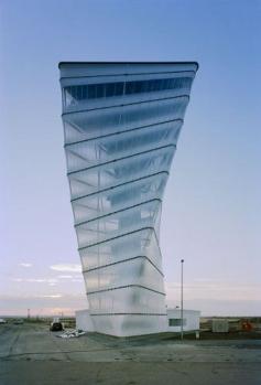 BBI-Infotower at Capital Airport in Berlin, Germany;  102 feet tall;  designed by Kusus + Kusus Architekten;  A massive reinforced concrete elevator core carries the weight of the entire structure, allowing the exterior envelope to have a feeling of delicacy and lightness.   Steel spiral stairs cantilever off the core with intermediate landings, and a view through the semi-transparent envelope. At the top are two observation decks, an encased platform and an open deck.   - photo by Schwarz